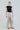 Double pinstripe high-waist wide-leg pants shown from the side, showcasing fluid wide-leg silhouette and tailored fit.